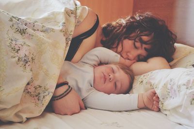 Close-up of mother and son sleeping on bed