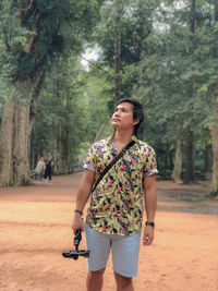 Young woman standing by tree