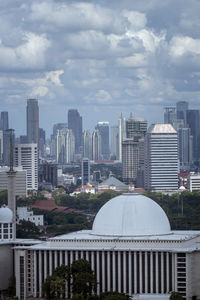 Buildings in city against cloudy sky