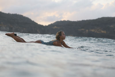 Female surfer in the ocean at sunset