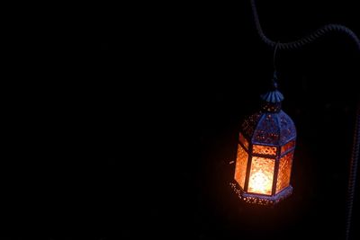 Low angle view of illuminated lighting equipment hanging at night