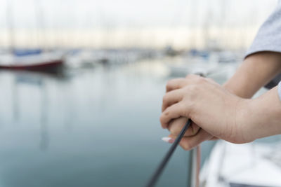 Cropped hands of woman on boat at harbor during sunset
