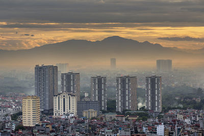 Modern buildings in city against sky during sunset