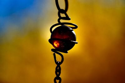 Close-up of metallic chain with yellow background