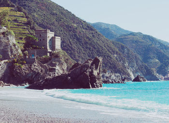 Scenic view of sea by mountains against clear sky