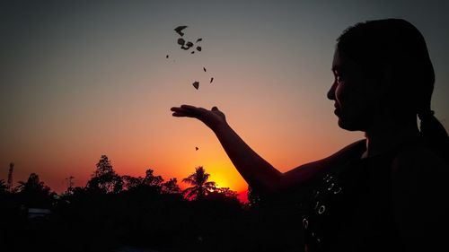 Side view portrait of silhouette woman holding orange sky during sunset