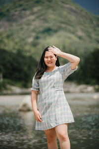 Young woman standing against waterfall