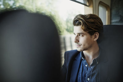 Thoughtful businessman looking through train window