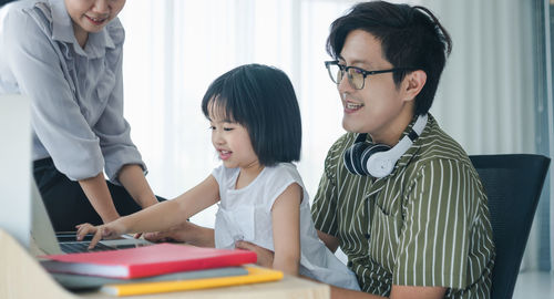 Man and woman reading book while sitting on table