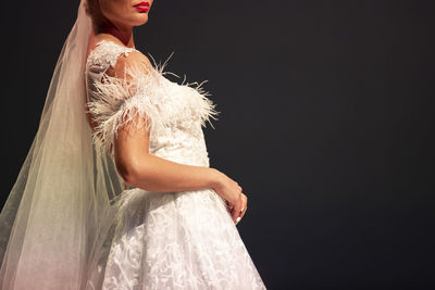 Midsection of woman standing against black background