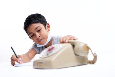 Portrait of boy holding camera over white background