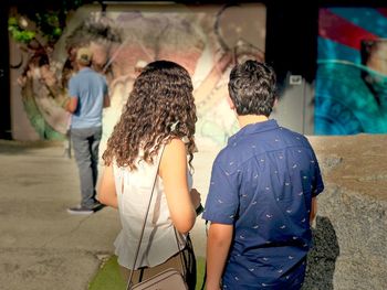 Rear view of couple standing on footpath during sunny day