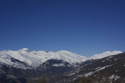 Scenic view of snowcapped mountains against clear blue sky