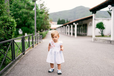 Portrait of cute girl standing against built structure