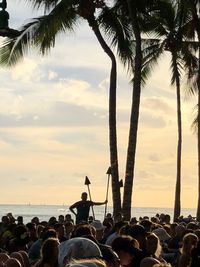 People at beach against sky during sunset