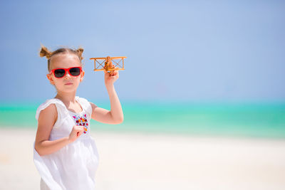 Young woman wearing sunglasses while standing against sea