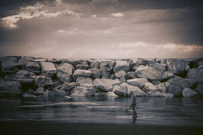 Side view of woman standing by rocks at beach