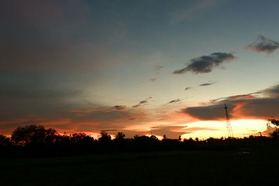 Silhouette trees on field against sky at sunset