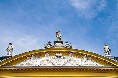 Low angle view of statues on historic building against blue sky