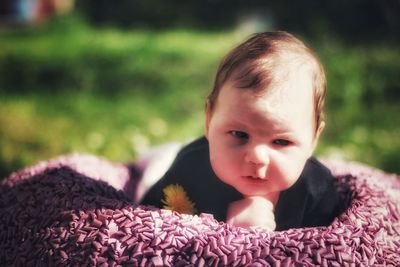 Close-up portrait of cute baby girl lying on blanket in park