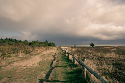 Footpath amidst field against sky