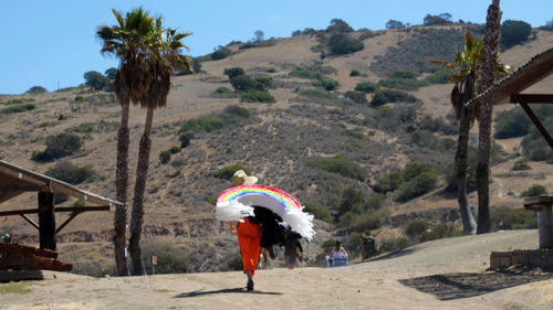 Rear view of woman walking on landscape against sky