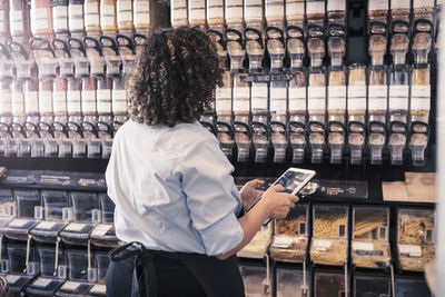 Female entrepreneur checking inventories while using digital tablet at organic shop