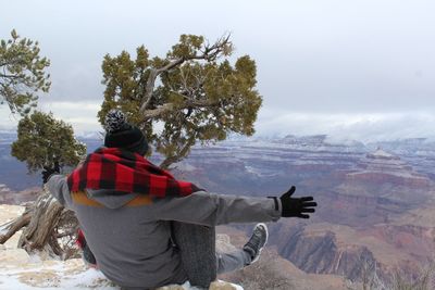 Rear view of woman sitting on mountain during winter