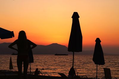 Silhouette man on beach against orange sky