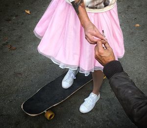 Low section of woman on skateboard taking joint from man