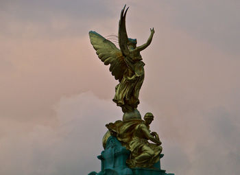 Low angle view of angel statue against cloudy sky