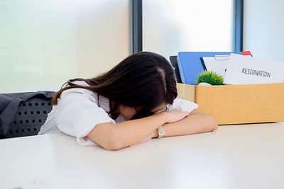 Stressed businesswoman resting head on desk in office