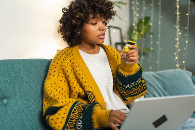 Young woman using laptop while sitting on table