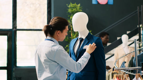 Side view of young woman using mobile phone while standing in office