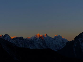 Scenic view of snowcapped mountains against clear sky during sunset