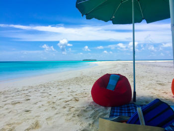 Deck chairs on beach against sky