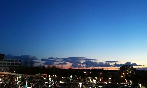 Illuminated cityscape against blue sky