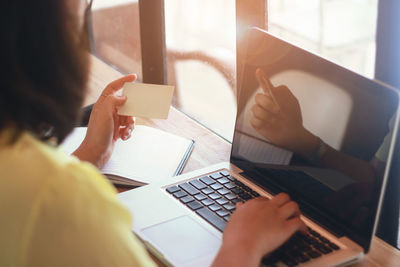 Midsection of businesswoman using laptop at desk in office