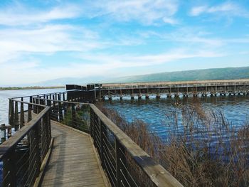 Boardwalk leading towards bridge against sky