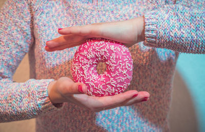 Midsection of woman holding donut at home