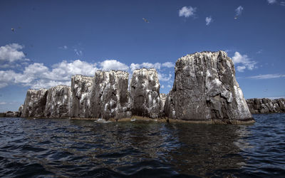 Rock formations in sea against sky