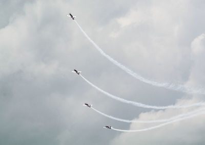 Low angle view of airplanes flying against blue sky