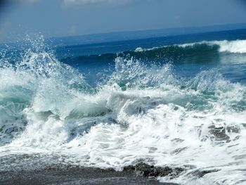 Waves splashing on sea against sky