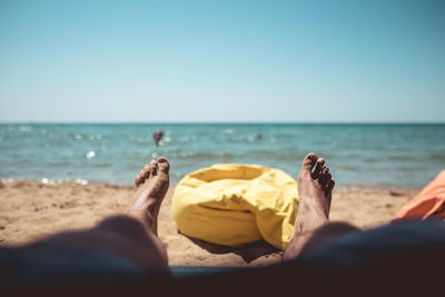 People relaxing on beach against clear sky