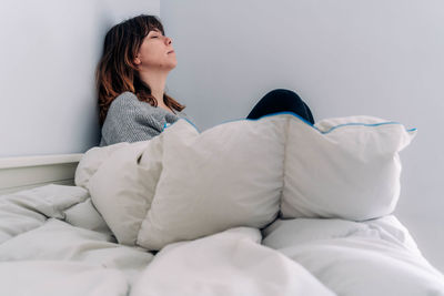 Woman sitting on bed at home