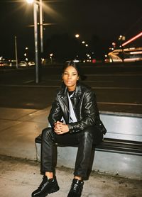 Portrait of young woman standing on street at night