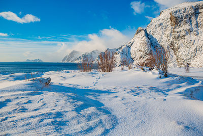 Snow covered landscape against blue sky