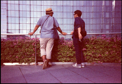 Rear view of friends standing on footpath