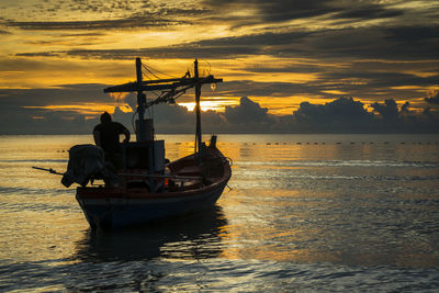 Boat in sea against cloudy sky during sunset