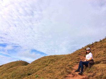 Full length of man sitting on land against sky